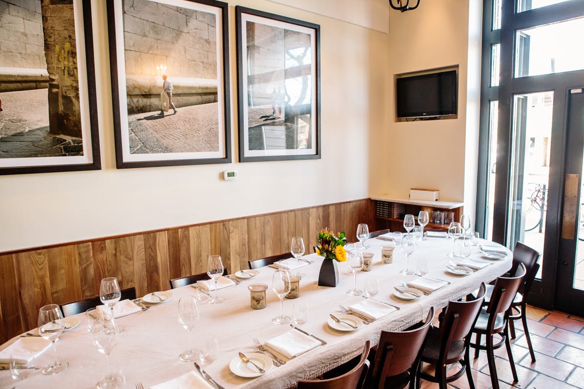 a large dining room table with cups and plates and two large paintings on the wall